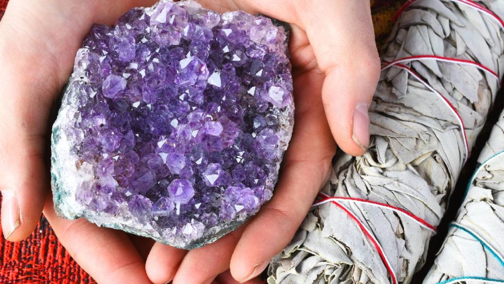 Two hands holding large amethyst crystal