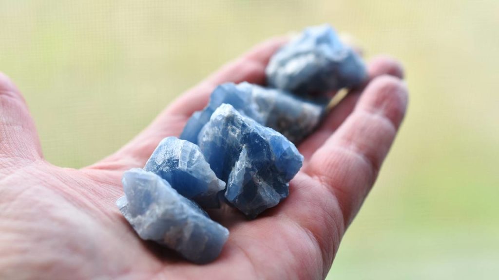 Hand holding raw blue calcite stones