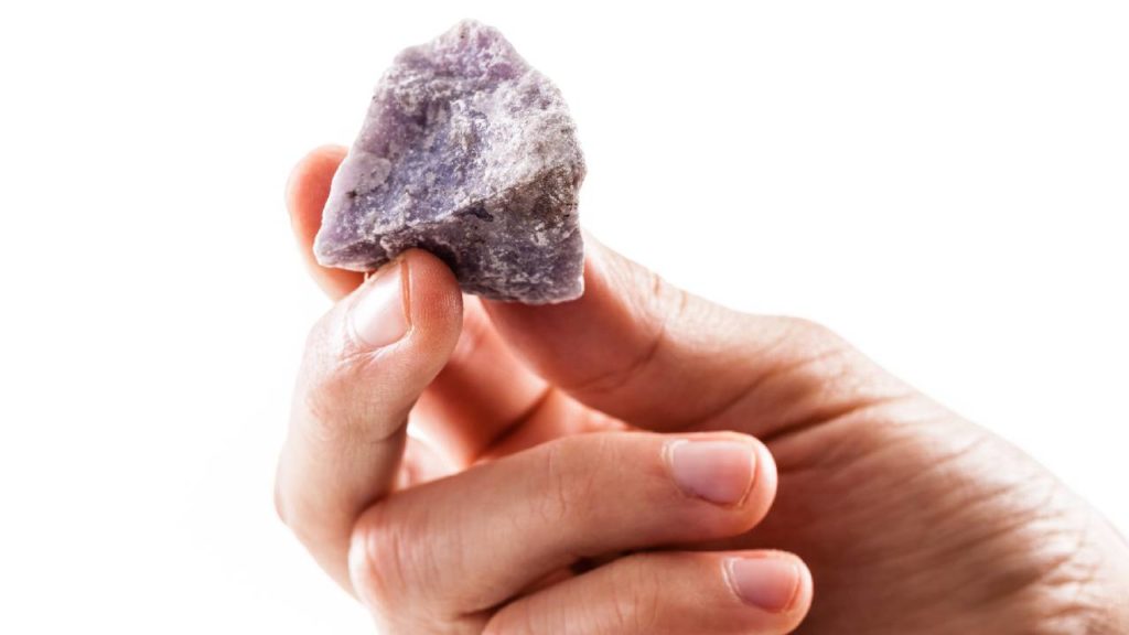 Hand holding rough lepidolite stone
