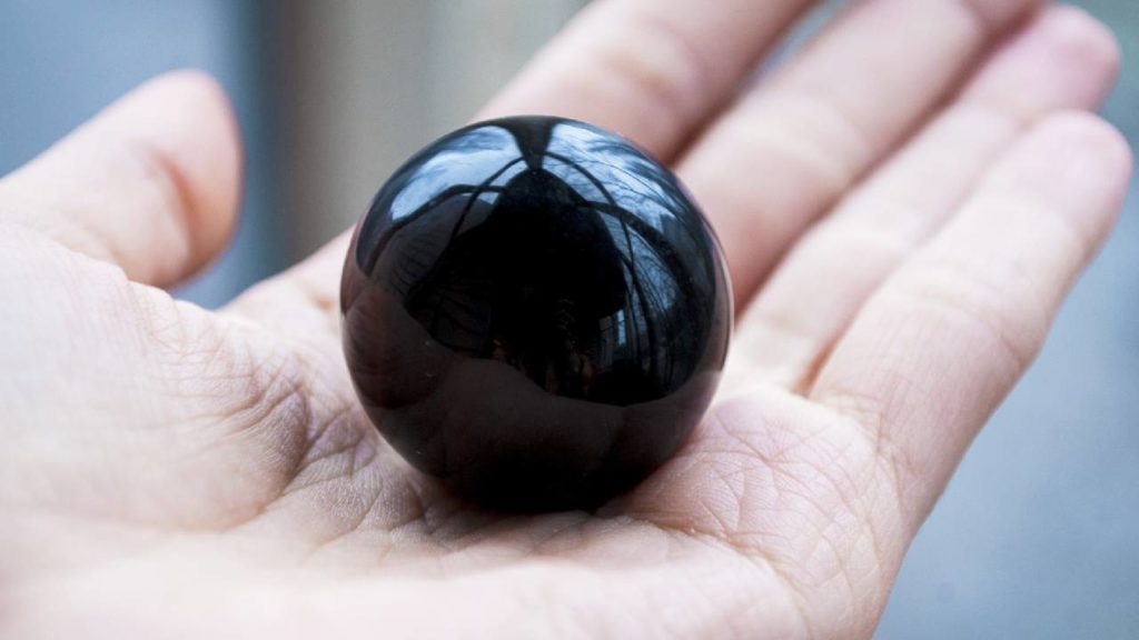 Holding a polished obsidian crystal sphere