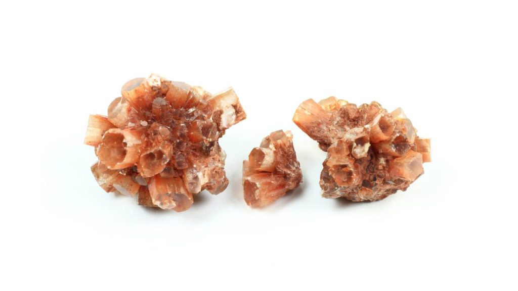 Three orange aragonite crystals