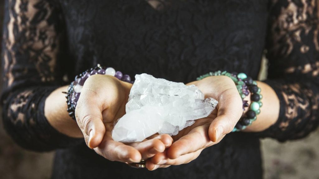 Woman wearing black holding clear quartz crystals