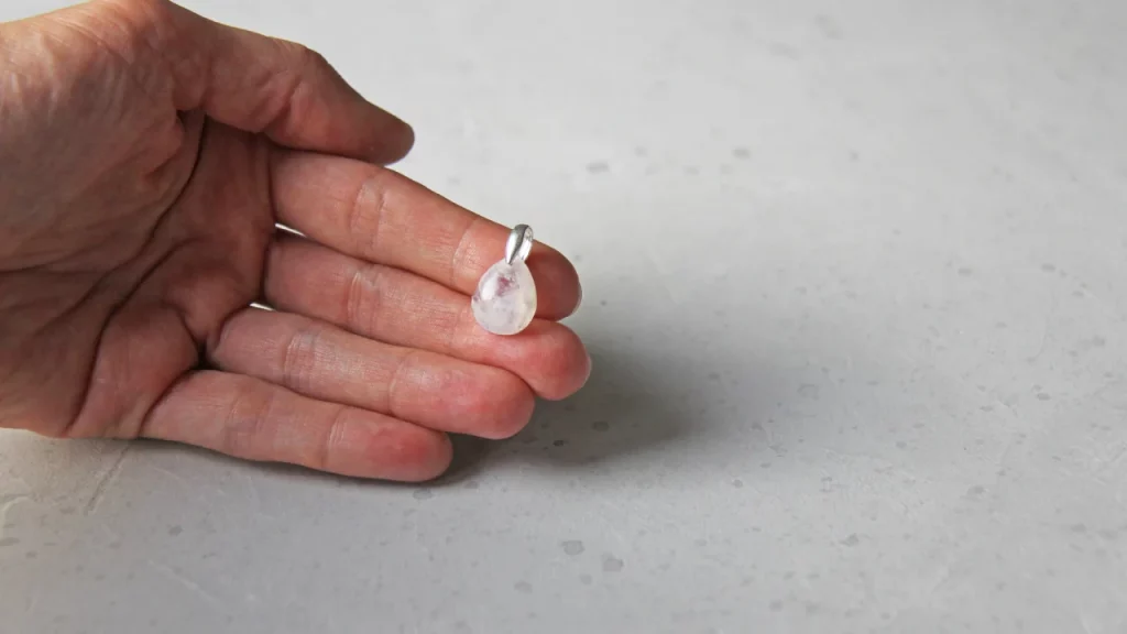 Hand holding moonstone crystal pendant